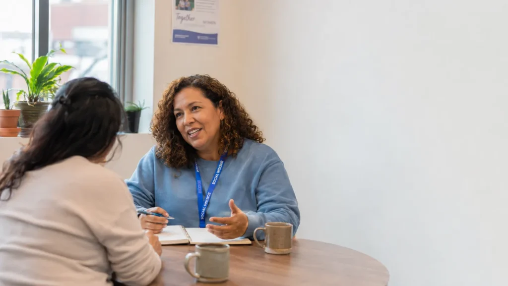 An adult social worker talking with a client in a warm, informal setting in the UK